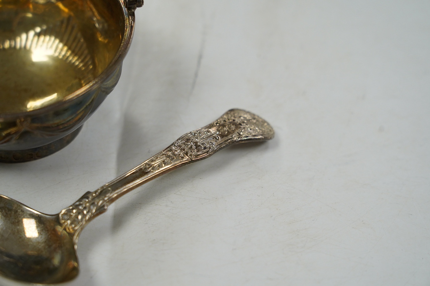 A George III silver small epergne basket, London, 1800, diameter 80mm, a large William IV silver caddy spoon and an Old Sheffield plate sauce bottle coaster. Condition - fair